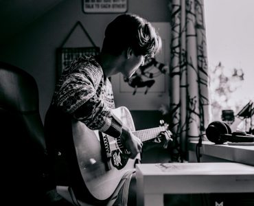 Guitarrista tocando el acorde de FA en una guitarra acústica